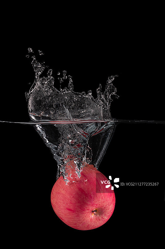 红色苹果落入水中凝固水花的瞬间图片素材