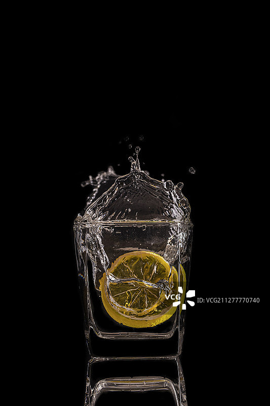 黄色柠檬片落入水中溅起凝固水花的瞬间图片素材