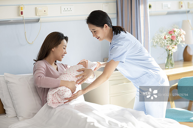 护士把新生婴儿抱给母亲图片素材