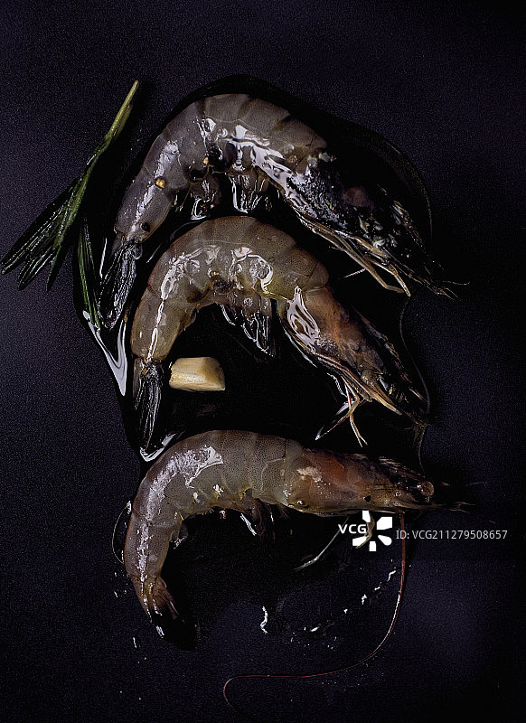 用迷迭香和橄榄油将生对虾放在黑色的表面上图片素材