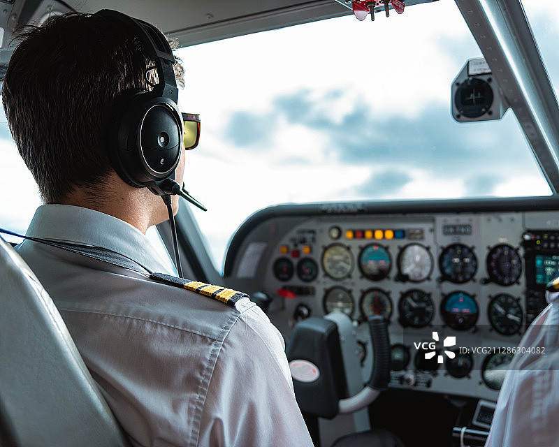 近拍飞行员驾驶飞机,飞行仪表板,飞行中,窗外,多云图片素材