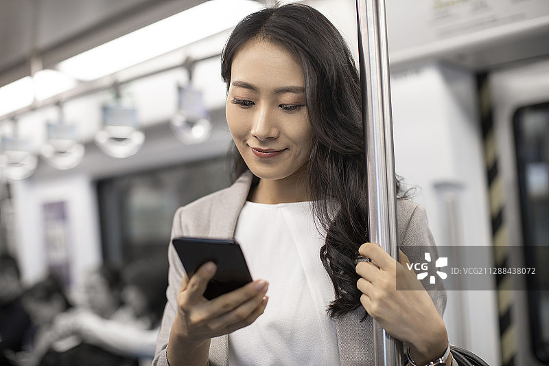 年轻商务女士在地铁里使用手机图片素材