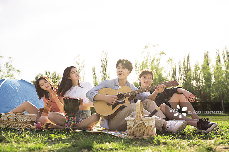 快乐的年轻人在户外野餐演奏音乐图片素材