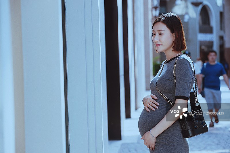 孕妇站在商店橱窗前图片素材
