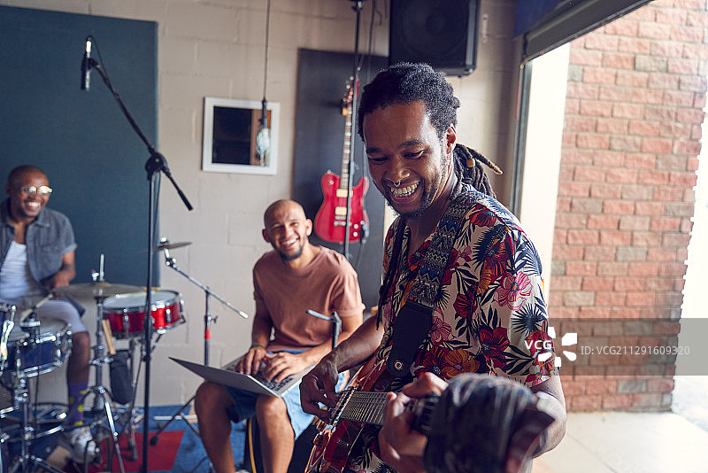 微笑的男音乐家在车库录音棚练习图片素材