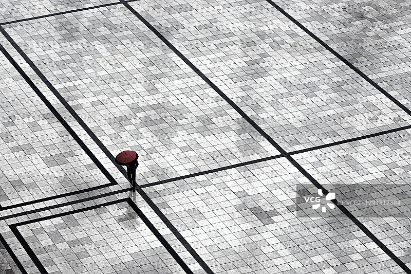一个人用红色伞穿过一个广场的高角度视图，维尔纽斯，立陶宛图片素材