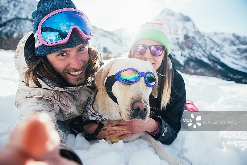 在冬天的山上，年轻夫妇和狗的观点图片素材