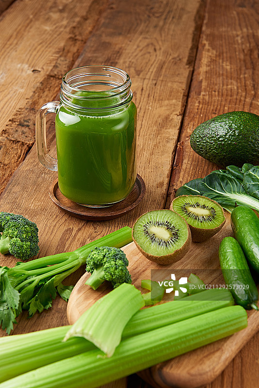 拍摄玻璃瓶里的绿汁和周围不同种类的蔬菜图片素材
