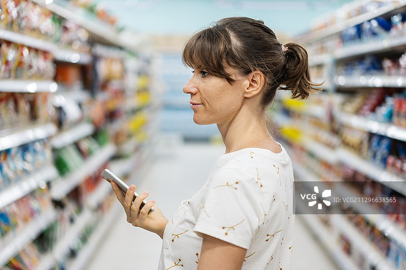 女人在超市用智能手机购物图片素材