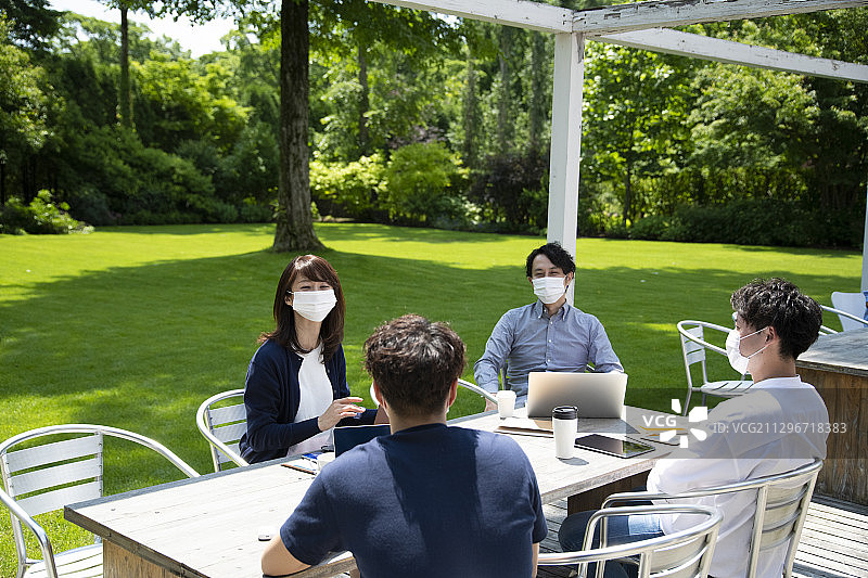 男男女女在户外办公室戴着口罩开会，这是新常态的办公风格图片素材