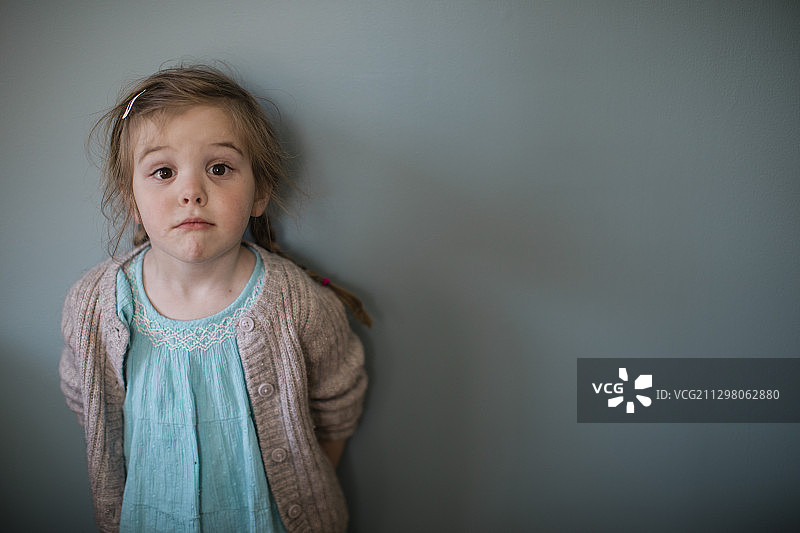 一个小女孩的肖像，在蓝色的墙上做鬼脸图片素材