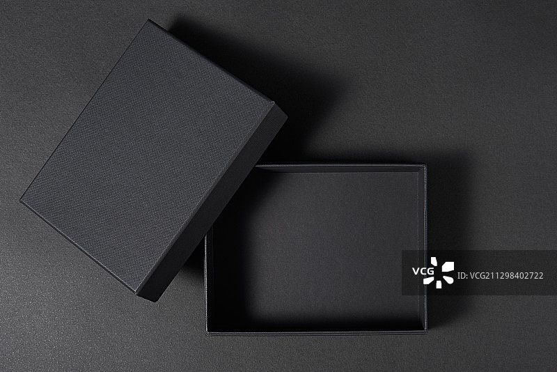 黑色的纸板箱，以黑色为背景，盖子打开图片素材
