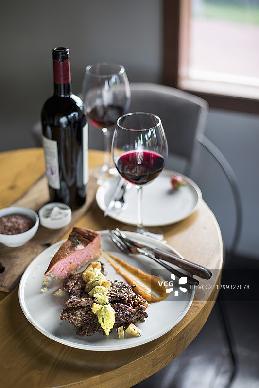 煎肉配酱料和装饰在盘子上，两个人的桌子，用玻璃杯和一瓶红酒图片素材