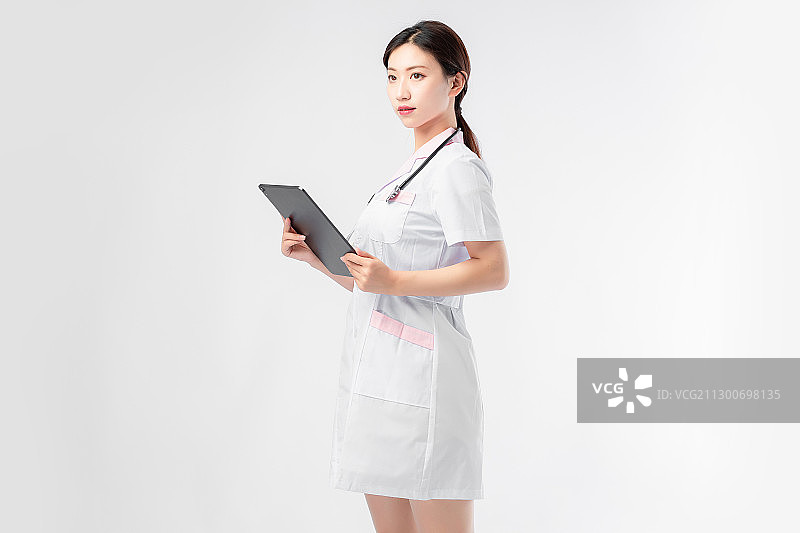 纯色背景里,拿着平板电脑的美丽的亚洲女护士图片素材