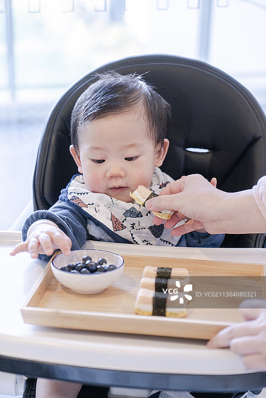 指导婴儿吃三文鱼寿司图片素材