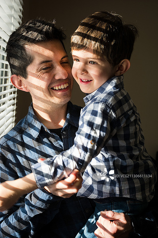 微笑的男孩和父亲在家的肖像，卡尔加里，阿尔布雷塔，加拿大图片素材