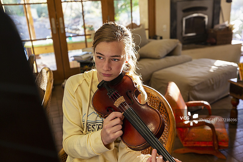 十几岁的女孩在家里拨弄她的小提琴弦图片素材