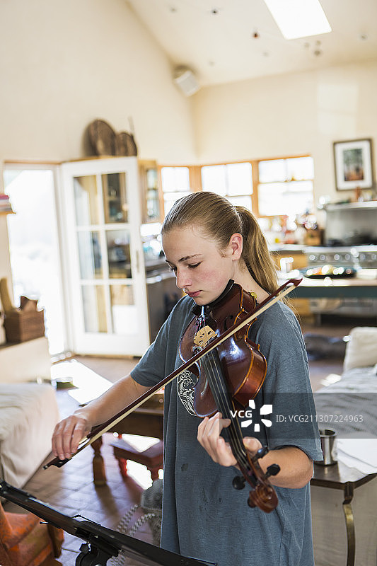 十几岁的女孩在家里拉小提琴图片素材