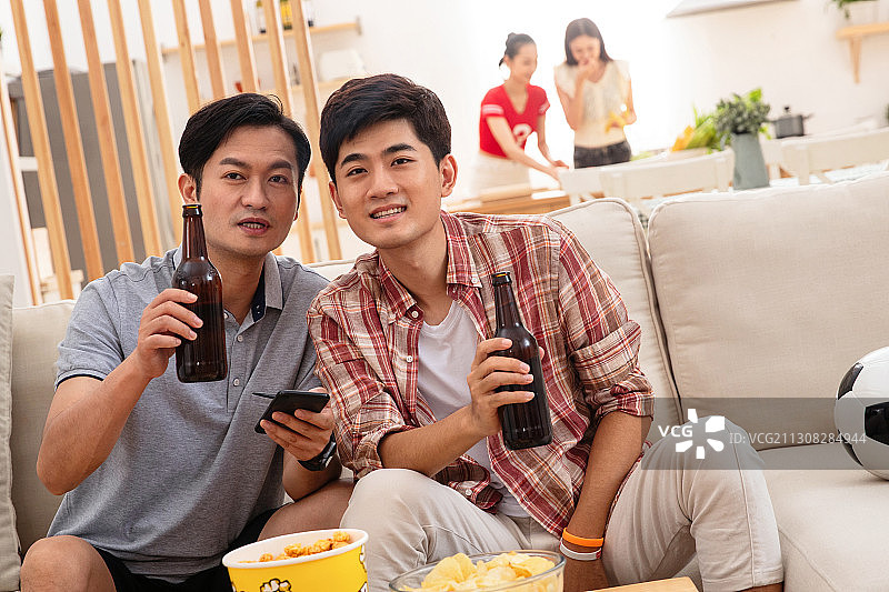 年轻朋友在家喝啤酒看球赛图片素材