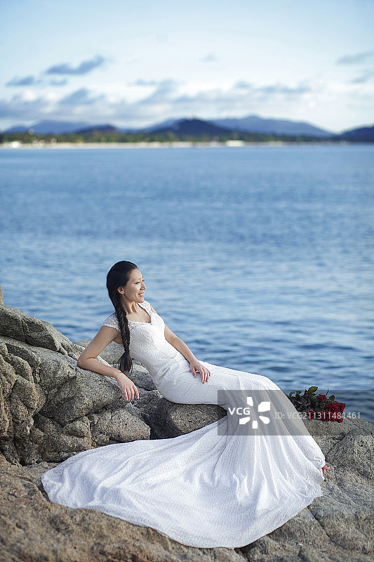一个新娘坐在海边岩石上图片素材
