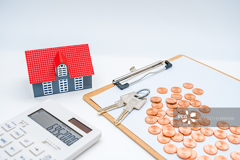白色背景下的房子模型、计算器、钱币和钥匙——买房子概念图片图片素材