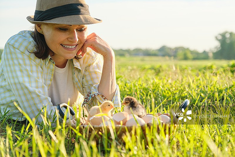 成熟的女人躺在草地上，篮子里有新生的小鸡图片素材