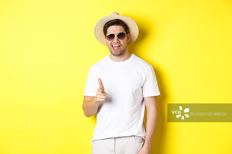 戴着太阳镜的微笑男子的肖像，站在黄色的背景下图片素材
