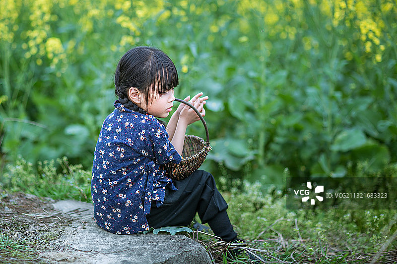 身穿村姑服在油菜花田里玩耍的小女孩图片素材