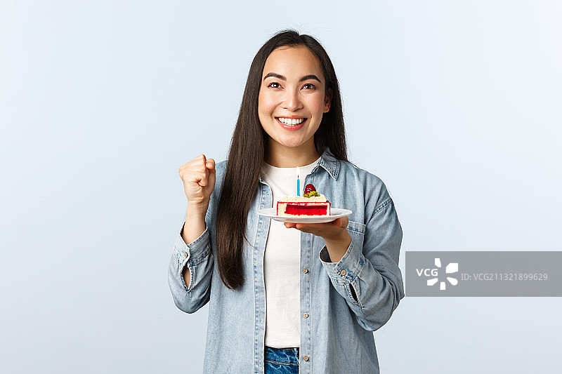 微笑的年轻女子的肖像拿着蛋糕，而站在白色的背景图片素材
