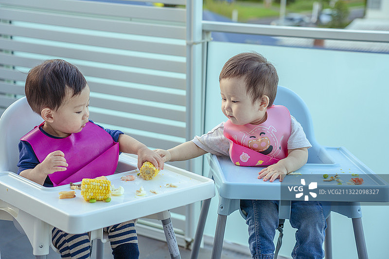 两个健康宝宝在婴儿餐桌上分享食物图片素材