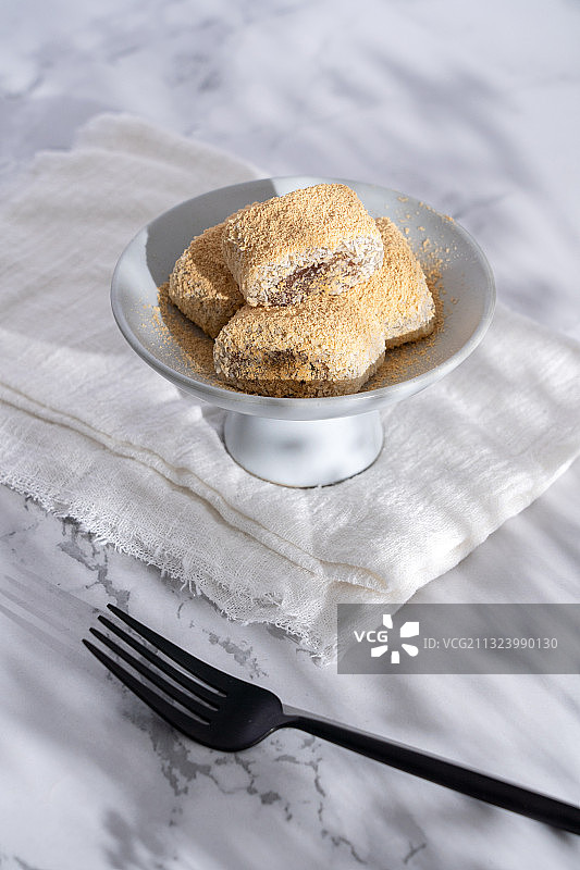 浅色纯色背景上盘子里的北京传统特色糕点小吃驴打滚图片素材