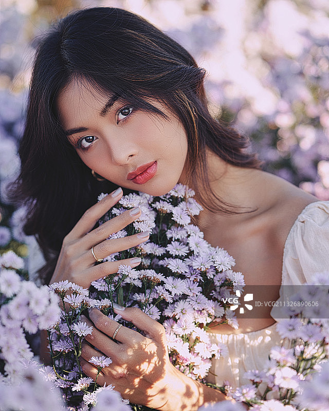 一个年轻的亚洲女人的肖像在紫色开花植物，Kuv Niam森林，泰国图片素材