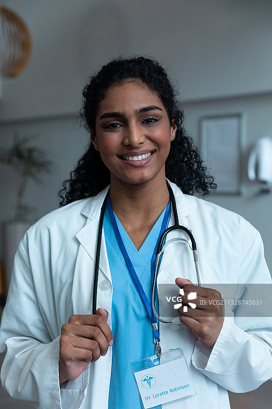 微笑的混血女医生的肖像与听诊器穿着白大褂在医院图片素材