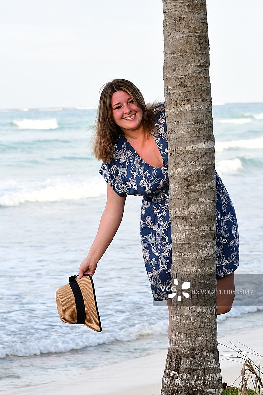 微笑女人的肖像站在树干在海滩图片素材