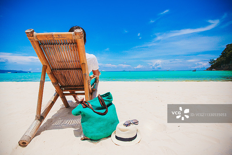 背靠天空坐在海滩椅子上的女人图片素材
