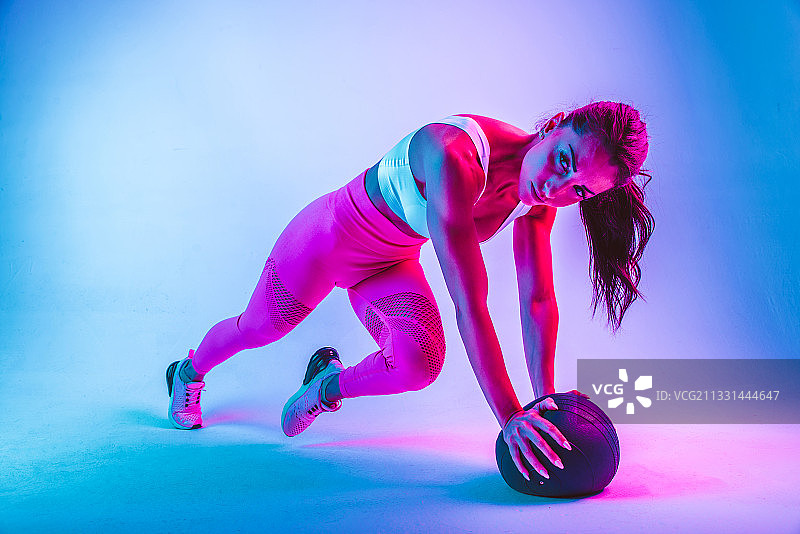 女子运动与实心球在蓝色的背景图片素材