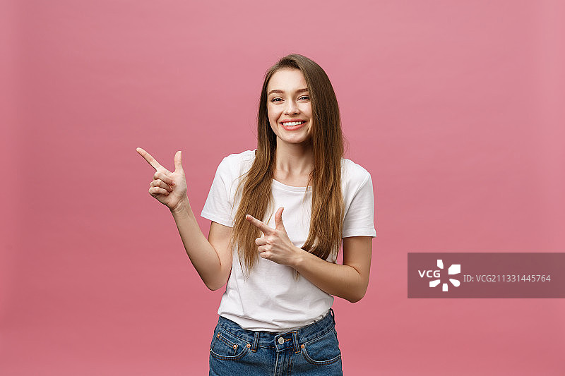 微笑的年轻女子肖像在粉红色的背景下做手势图片素材