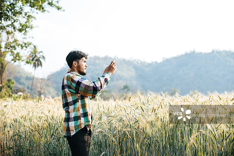 一名男子站在田野上，对着天空拍照图片素材