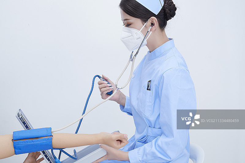 手拿血压测量仪为患者诊治量血压的女性护士图片素材