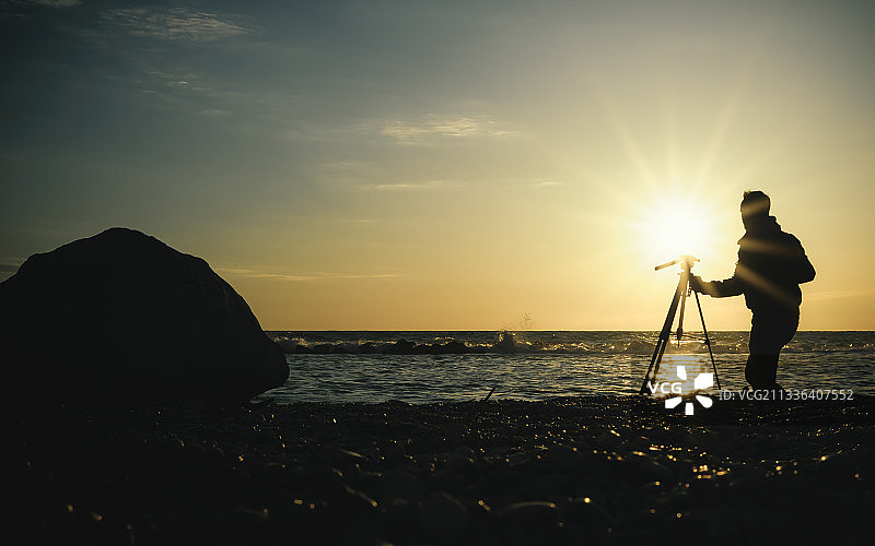 意大利安科纳，蒙特卡罗，日落时分，站在海滩上拍摄剪影的男子图片素材