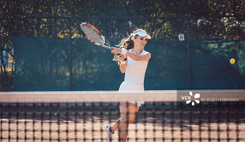 在球场上用力打网球的女人图片素材