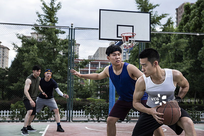 四个青年男子在学校篮球场打篮球比赛图片素材