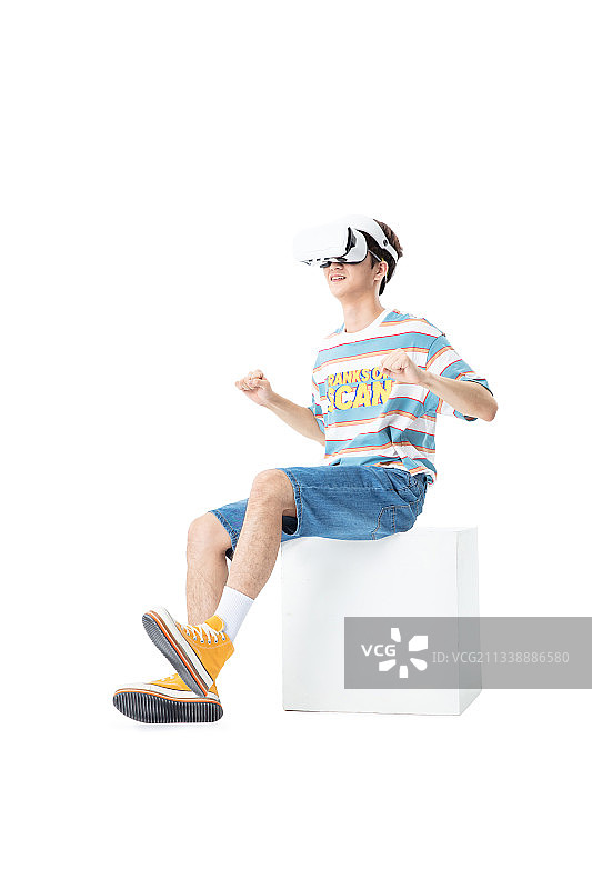 坐在木箱子上带着VR的年轻男生图片素材