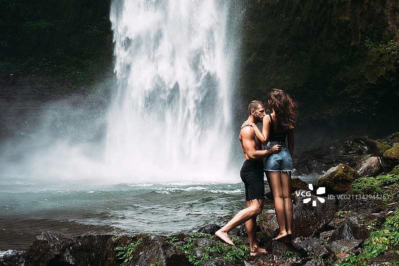 一对年轻夫妇站在瀑布前图片素材