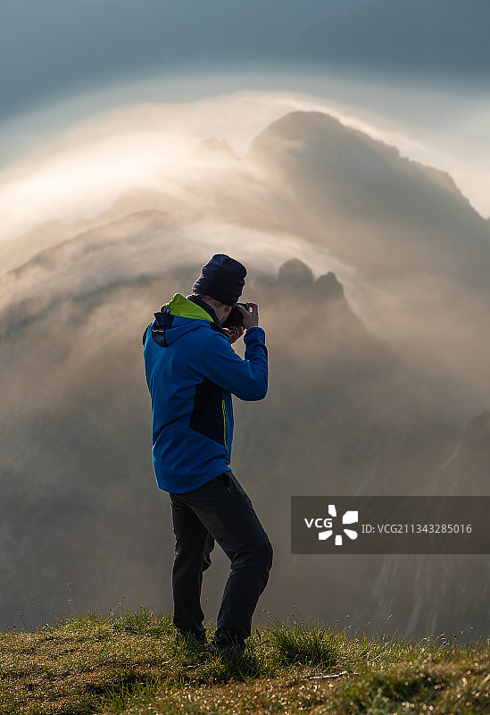 一名男子站在山上拍摄日落时分的天空，罗马尼亚图片素材