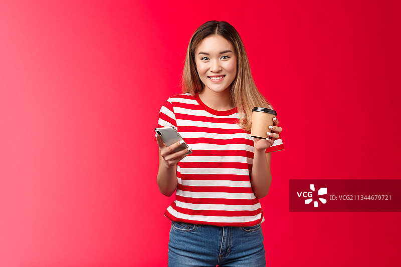微笑的年轻女子肖像拿着咖啡杯在红色的背景图片素材