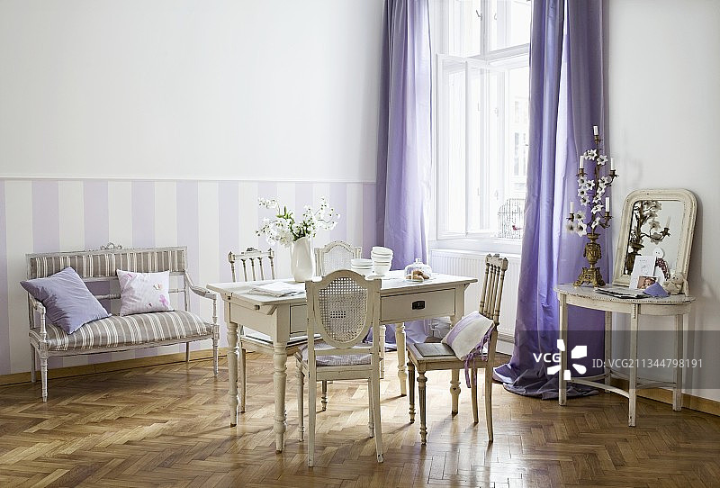 古斯塔夫风格的木桌周围环绕着古老的法国椅子，长凳靠在紫色和白色条纹的墙壁上图片素材