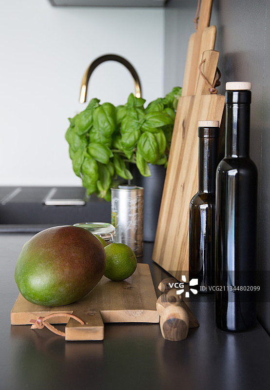木板上放着芒果，厨房桌面上放着油瓶和罗勒图片素材