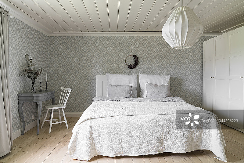 白色衣柜，双人床，卧室书桌和图案墙纸图片素材