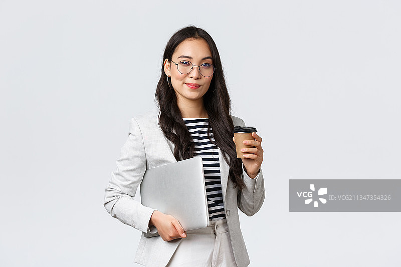 年轻女子手持笔记本电脑，站在白色背景下图片素材